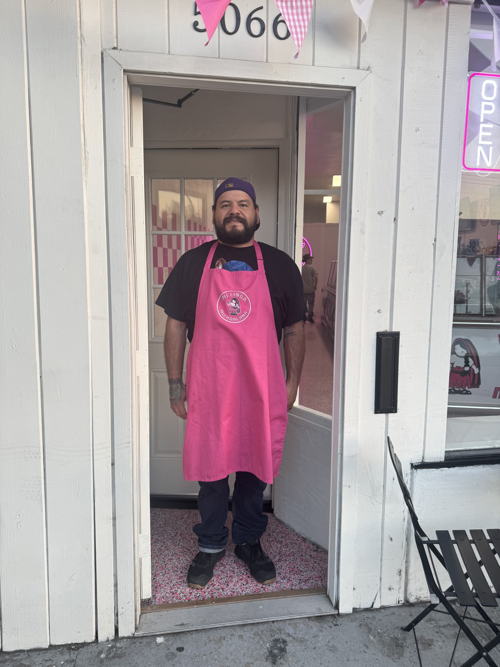 Reuben, the owner of Mi Linda Michoacana, standing in the doorway wearing the shop's pink apron