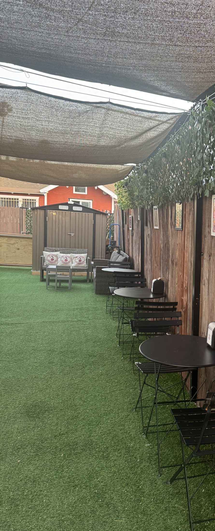 Wide view down the turf runway of the Dog Lounge, shaded by sail canopies